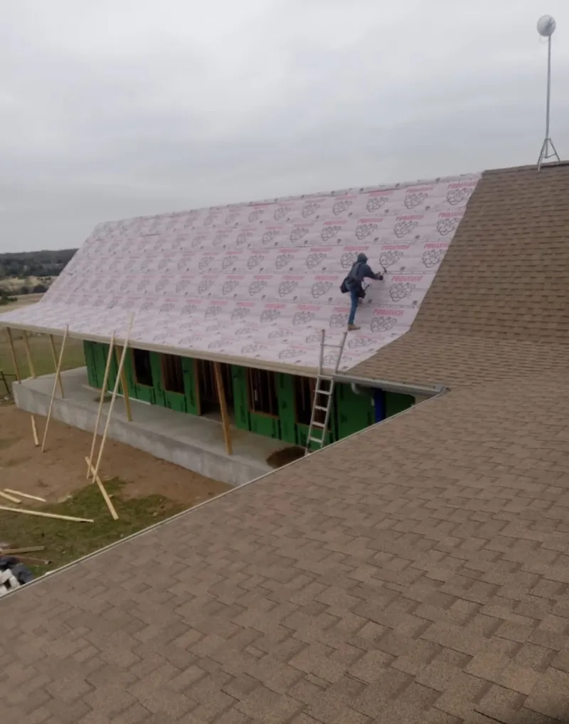 Worker preparing underlayment for a metal roof installation in North Ogden
